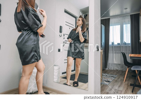 young woman grooming her hair in modern apartment, concept of daily beauty routines and personal care 124910917