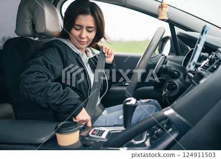 Woman Prepares For A Long Car Trip And Fastens Seatbelt 124911503