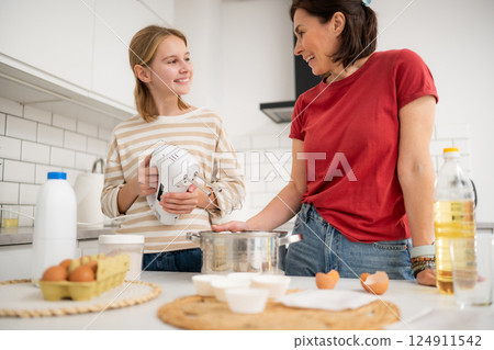 Happy Little Girl And Mother Baking And Mixing Dough In The Kitchen Happy Little Girl And Mother Baking And Mixing Dough In The Kitchen 124911542