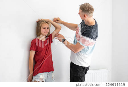 Happy Father Measuring Smiling Daughter's Height At Home 124911619