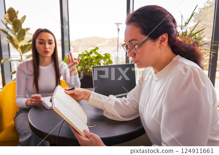 Two professional Caucasian women discussing business plans in a cafe during lunch break. Concept of productivity and collaborative online marketing. Mid shot Two professional Caucasian women discussing business plans in a cafe during lunch break. Concept of productivity and collaborative online marketing. Mid shot 124911661