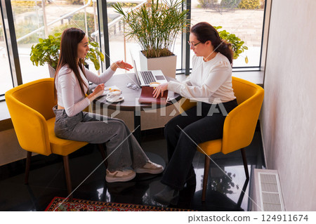 Two creative women exchanging branding tips during lunch. Concept of innovation and teamwork. Side view Two creative women exchanging branding tips during lunch. Concept of innovation and teamwork. Side view 124911674