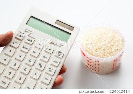 手拿著量杯的米和一個計算器 124912414
