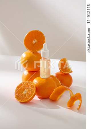 Vertical photo of transparent serum dropper bottles placed on ripe citrus. Three oranges are stacked high and others cut into different shapes. Orange peels are thinly sliced to spiraled. Vertical photo of transparent serum dropper bottles placed on ripe citrus. Three oranges are stacked high and others cut into different shapes. Orange peels are thinly sliced to spiraled. 124912558