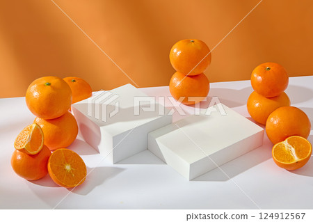 The shadows of stacks of oranges are reflected on the rectangular white podium. Round oranges with rough skin and juicy flesh. Oranges are a tropical fruit with many benefits and vitamins. 124912567