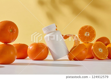 Orange peel sliced to wavy rolled around an orange. White medicine bottle without label. Oranges and tangerines placed on top of each other randomly, some cut in half to show juicy orange flesh. 124912579