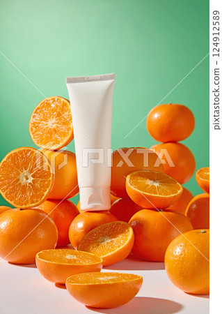 Mockup of cosmetic cream tube placed on many ripe oranges. Citrus cut in half placed around, presented on white table. Orange peel is rough with tiny holes, orange flesh is juicy and vibrant. Mockup of cosmetic cream tube placed on many ripe oranges. Citrus cut in half placed around, presented on white table. Orange peel is rough with tiny holes, orange flesh is juicy and vibrant. 124912589