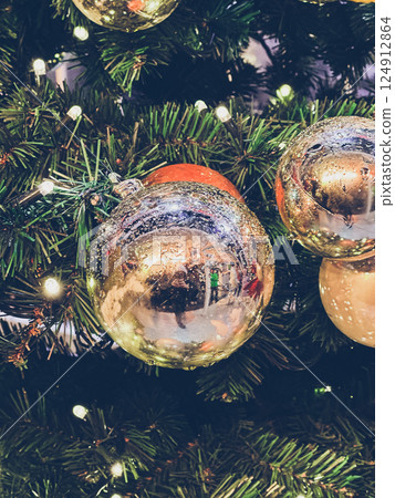 Tree with many shiny gold ornaments hanging from it 124912864