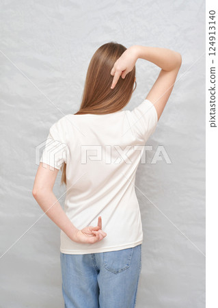 Young caucasian female gesturing with hand behind back in white t-shirt Young caucasian female gesturing with hand behind back in white t-shirt 124913140
