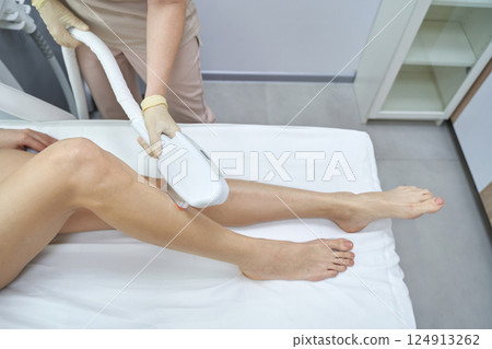 Female adult receiving laser hair removal treatment on legs in a modern clinic Female adult receiving laser hair removal treatment on legs in a modern clinic 124913262