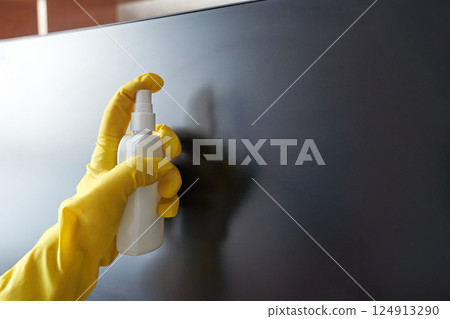 Gloved hand cleaning screen with spray bottle for hygiene and maintenance Gloved hand cleaning screen with spray bottle for hygiene and maintenance 124913290