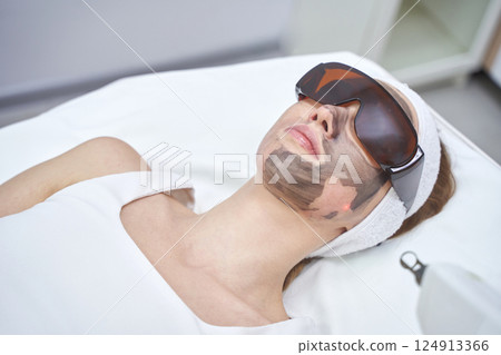 Female adult receiving carbon laser facial treatment in spa setting 124913366