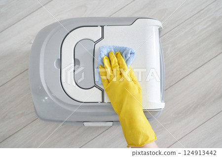 Cleaning cloth and gloved hand on trash bin lid for hygiene maintenance on wood Cleaning cloth and gloved hand on trash bin lid for hygiene maintenance on wood 124913442