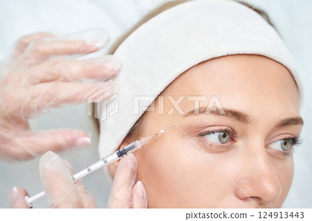 Caucasian young female receiving cosmetic injection for facial rejuvenation Caucasian young female receiving cosmetic injection for facial rejuvenation 124913443
