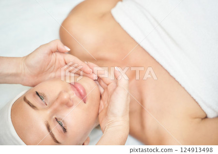 Female caucasian adult relaxing during spa facial treatment with gentle massage Female caucasian adult relaxing during spa facial treatment with gentle massage 124913498