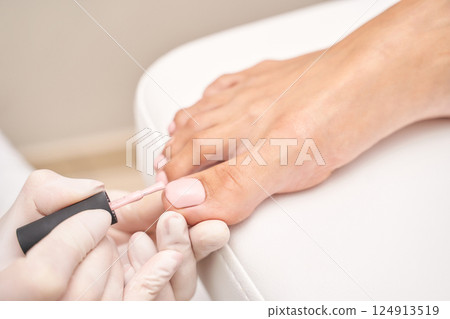 Female pedicure with pink nail polish on caucasian feet in salon Female pedicure with pink nail polish on caucasian feet in salon 124913519