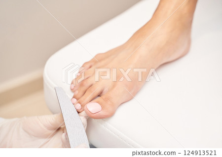 Caucasian female receiving professional pedicure nail file treatment in spa 124913521