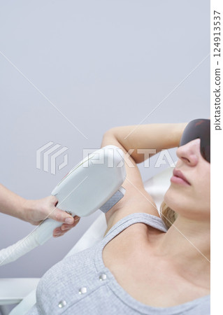 Caucasian female receiving laser hair removal treatment on armpit in cosmetic Caucasian female receiving laser hair removal treatment on armpit in cosmetic 124913537