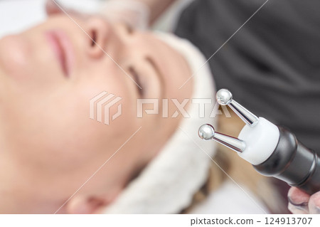 Caucasian female receiving facial treatment with advanced microcurrent device 124913707