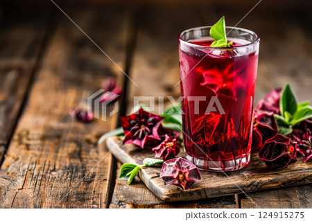 Glass of red drink with a bunch of flowers on the table. 124915275