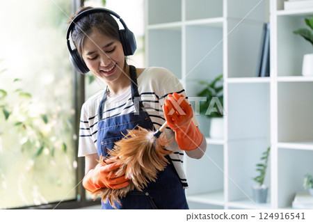 Smiling cleaner with headphones dusting in bright office Smiling cleaner with headphones dusting in bright office 124916541