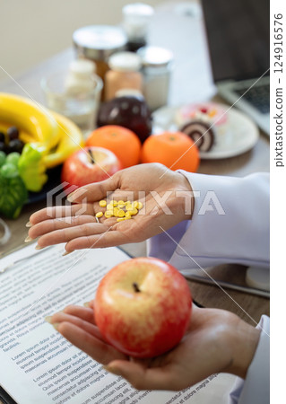 Nutrition and Wellness. A nutritionist comparing medication with healthy food choices. 124916576