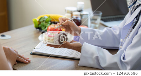 Nutrition and Wellness. A doctor demonstrating healthy dessert options and sugary treats to a patient. 124916586