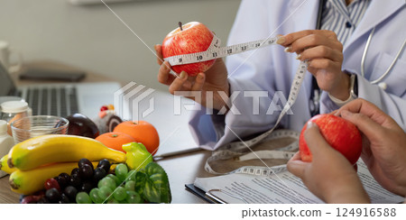 Nutrition and Wellness. A healthcare provider uses a measuring tape to emphasize portion control. 124916588