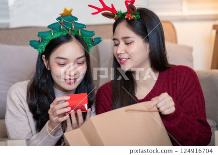 Lesbian couple sharing Christmas joy with thoughtful gifting Lesbian couple sharing Christmas joy with thoughtful gifting 124916704