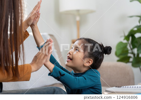 Play and Interaction. A girl joyfully interacts with her mother in a fun high-five moment. 124916806
