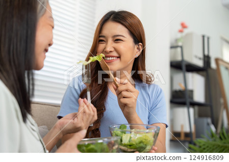 Family Bonding and Healthy Living. A daughter and her mother enjoying a light salad while sharing smiles and laughter. 124916809