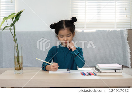 Concentration and Creativity. A young girl writes in her notebook at home, reflecting on her learning journey. Concentration and Creativity. A young girl writes in her notebook at home, reflecting on her learning journey. 124917082