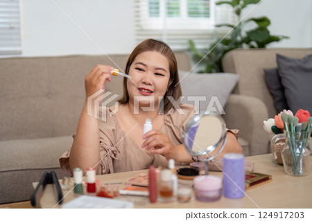 Beauty and Skincare. A woman exploring beauty oils while smiling in her cozy makeup space. Beauty and Skincare. A woman exploring beauty oils while smiling in her cozy makeup space. 124917203