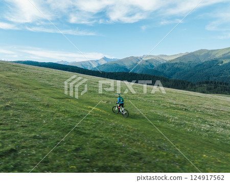 Woman riding mountain bike on beautiful flowering grassland mountain top 124917562