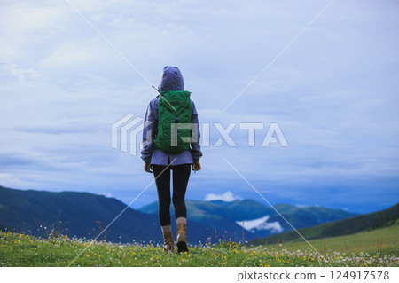 Woman hiker on beautiful flowering grassland mountain top Woman hiker on beautiful flowering grassland mountain top 124917578
