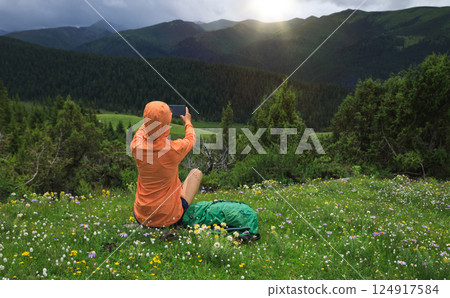 Hiking woman taking photo with mobile phone on high altitude forest mountains Hiking woman taking photo with mobile phone on high altitude forest mountains 124917584