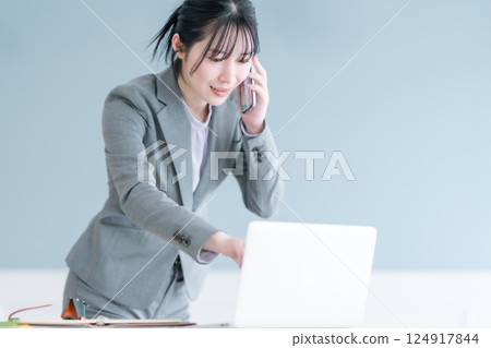 A young career woman talking on the phone while checking documents on her smartphone 124917844