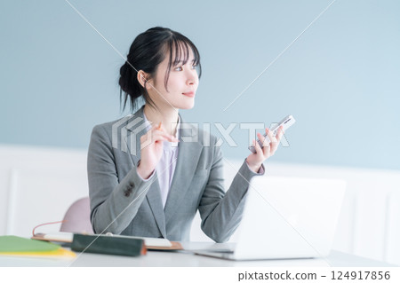 A young career woman taking notes while looking at her smartphone A young career woman taking notes while looking at her smartphone 124917856