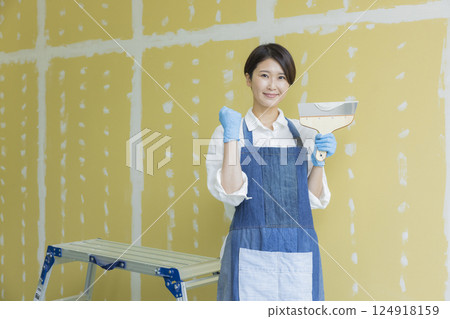 一名婦女正在為石膏板塗膩子 124918159