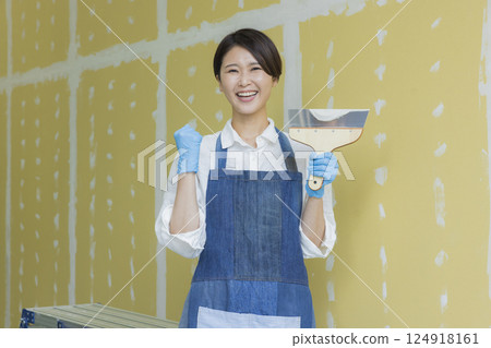 A woman applying putty to plasterboard 124918161