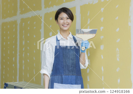 一名婦女正在為石膏板塗膩子 一名婦女正在為石膏板塗膩子 124918166
