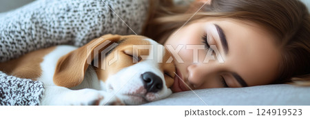Cozy beagle puppy snuggles with young person in peaceful slumber 124919523