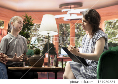 In a confidential therapy session teenage girl and her mother discuss personal troubles and emotional struggles. The therapist provides guidance for navigating adolescence and behavioral therapy. 124920224