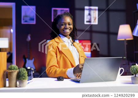 Portrait of smiling freelancer in home office checking analytics statistical data sets on laptop. Happy young woman optimizing key performance indicators in apartment workspace 124920299