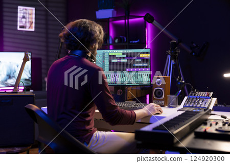 Sound engineer working in his home studio with daw software on computer and mixing tools, creating music. Producer mixing and mastering soundtracks, signal processing acoustical engineering. 124920300