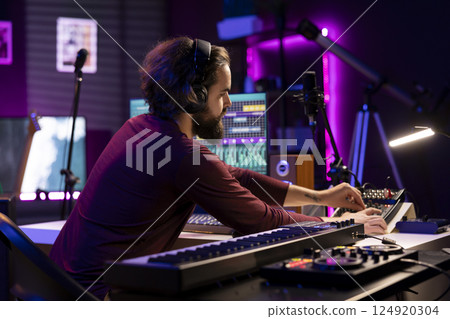 Musical producer working on artistic post production with editing and synchronizing recorded songs. Artist songwriter using digital audio workstation interface to manipulate tunes, audio effects. Musical producer working on artistic post production with editing and synchronizing recorded songs. Artist songwriter using digital audio workstation interface to manipulate tunes, audio effects. 124920304