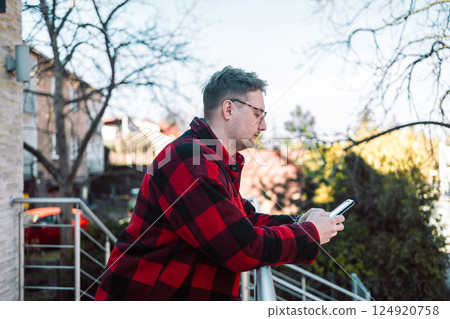 Young blond man with glasses looking at phone on street Young blond man with glasses looking at phone on street 124920758