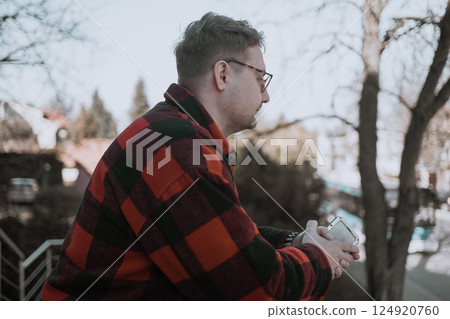 Young blond man with glasses looking at phone on street Young blond man with glasses looking at phone on street 124920760