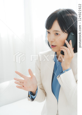 A middle-aged career woman using gestures to talk to the person on the other end of the phone 124921922