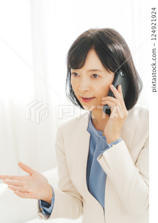 一位中年職業婦女用手勢與電話另一端的人交談 一位中年職業婦女用手勢與電話另一端的人交談 124921924
